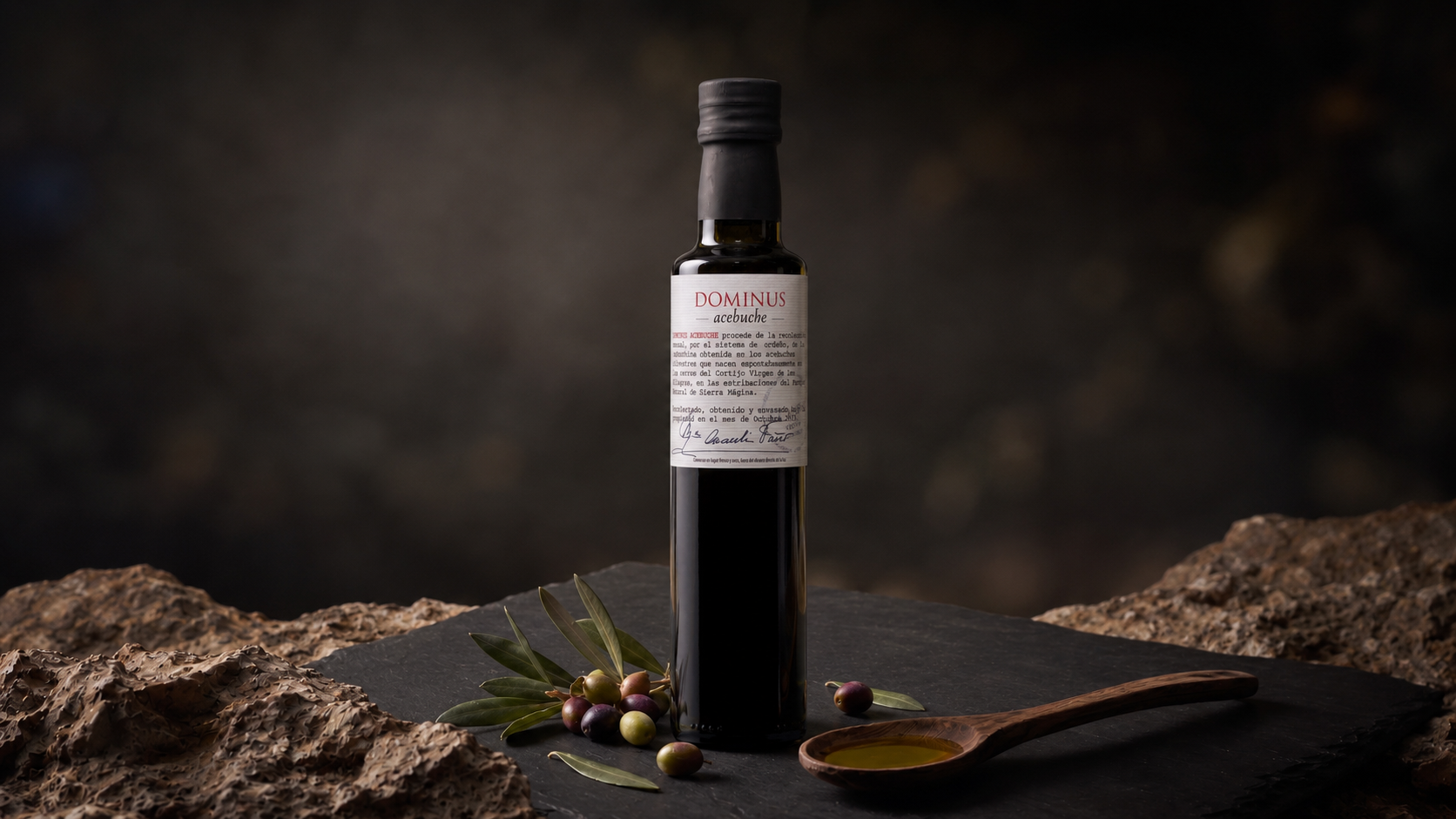 Botella de Dominus Acebuche sobre piedra negra con acebuchinas y cuchara de madera